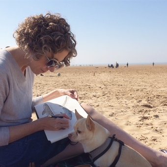 Dani Williams on the local beach with sketchbook and Riley chihuahua.