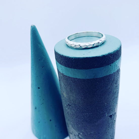 sterling silver textured stacking ring sat on a concrete jewellery stand