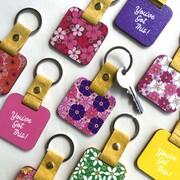 a set of colourful keyrings with 70's style flower prints and words of encouragement printed on them