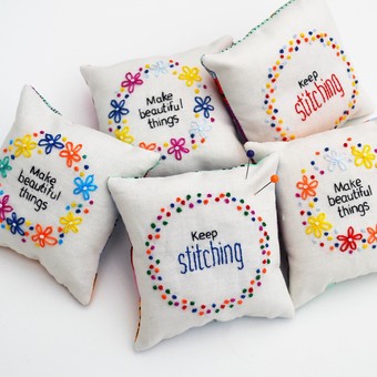a stack of hand embroidered pincushions with the words 'make beautiful things'