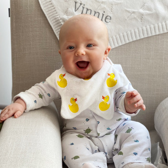 Baby wearing a Dribble Days bib embroidered with Ducks