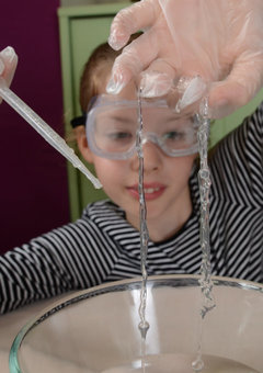 A child does an experiment from Letterbox Lab's Investigate Box: Marvellous Mixtures. They mix sodium alginate with calcium lactate to make slime.