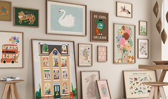 A gallery wall showing children's and nursery art prints, featuring safari animal, a partys bus , swan. large house , vase of flowers and  and various animals.