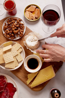 Amazing cheese and crackers board cutting into cheese with a glass of wine 