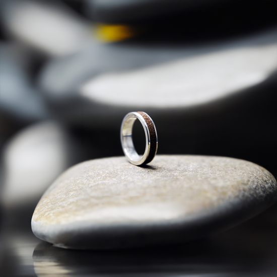 A ring inlaid with sand sitting on a rock