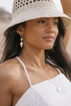 A model wearing shell earrings at the beach