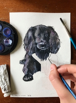 Illustrator, Gaby, working on a painting of a black dog