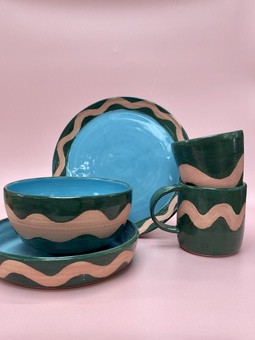 Hills collection of tableware featuring pink wave in raw clay on a dark green glaze with blue inside