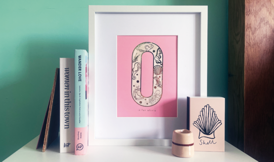 Styled bedroom layout with personalised pink letter print, books and box of matches