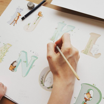 artist's hand Illustrating a children's alphabet picture with watercolour paints