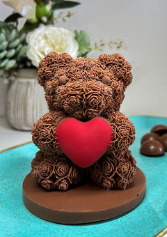A velvety Belgian milk chocolate bear adorned with delicate roses, symbolizing love. The bear's shell holds chocolate treasures, hazelnut-filled bars.