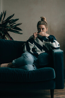 Founder of Slow Sunday, Liz, sat on a blue velvet sofa drinking a cup of tea.