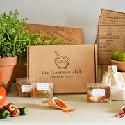 A Teaspoon Club box is front and centre with spice packets displayed around it, as well as fresh chillies and oregano