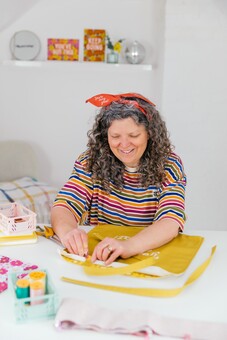 lady in a stripy top and head hairband pinning together a mustard coloured tote bag