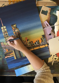 A close up of Holly Anne Blake's arm as she creates a collage of the New York City skyline