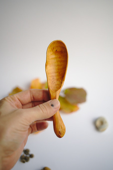 Holding up a hand carved wooden scoop that exemplifies the imperfect nature of our handmade home wares.