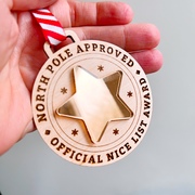 A wooden medal with a gold mirror star and the words "North Pole approved - official nice list award" engraved into it.