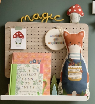 Nursery shelf and pegboard with Whiskers character cushion, books and mushroom decoration.