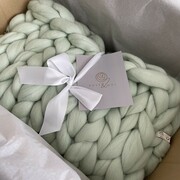 A Peppermint Green baby sleeping packaged in a box with a white ribbon tied in a a bow and Rose & Wül Care Card.
