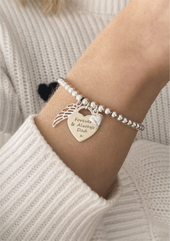 A silver charm bracelet worn on a model wearing a white jumper