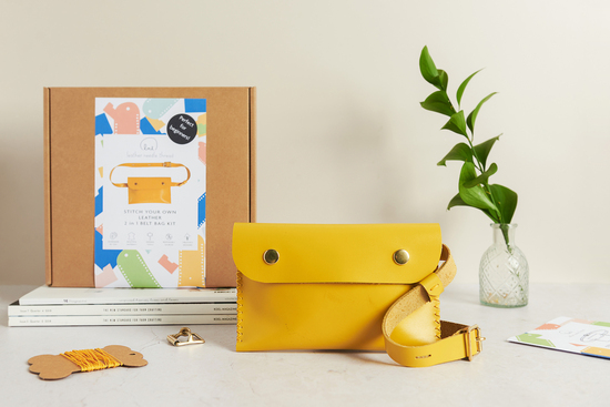 A yellow leather belt bag in front of a leathercraft kit box
