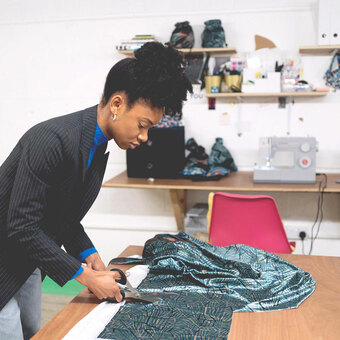 Owner of OlaOla, Ola Olayinka cutting fabric