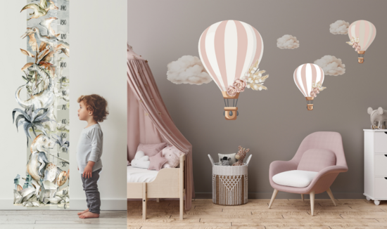 A little boy stands next to a wall sticker "Dinosaur" height chart & large blush pink hot air balloon stickers