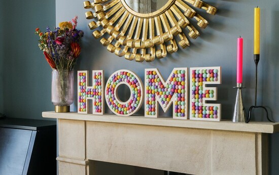 Pom pom filled plywood letters spelling HOME