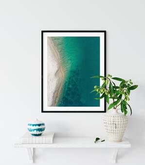 Aerial photography print displayed in a frame on a shelf with a plant