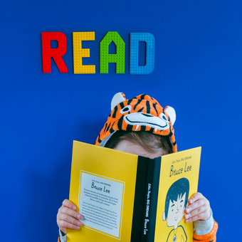 Lego compatible letters spelling 'read' with a child reading a book