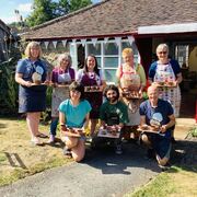 a group of pottery course participants proudly showing the pots they made on the potter's wheel in the pottery garden at eastnor pottery herefordshire
