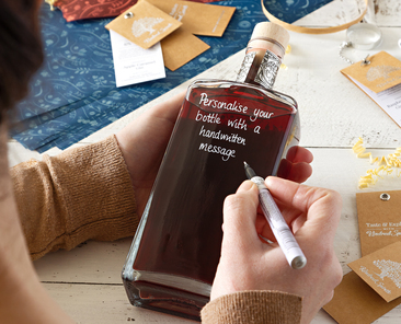 a handwritten message is being added to a bottle of craft spirits