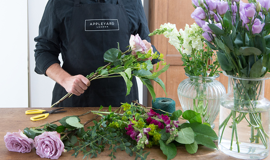 Appleyard florist in a black branded apron preparing fresh flowers