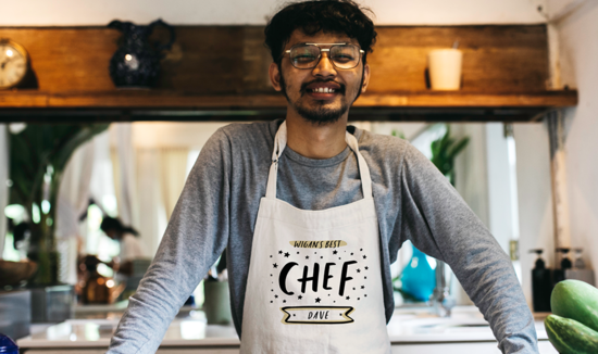 Man wearing a personalised Studio Yelle apron reading "Wigan's Best Chef, Dave"