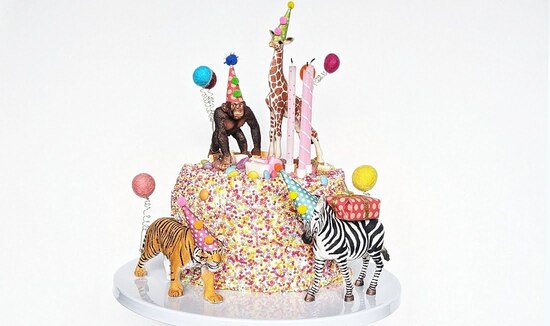 A safari set of animal cake toppers surrounding a birthday cake