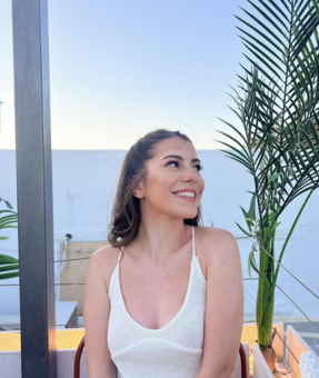 Shannon standing holding a yellow balloon in front of a window