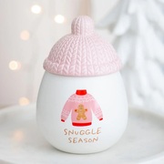 Wax burner, with a snuggly gingerbread jumper printed on the front and the words ' snuggle season'. The burner has a cermaic pink lid shaped like a knitted hat