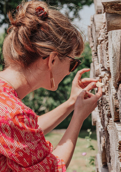 Nic behind the scenes on a photoshoot styling a pair of wood and hand beaten brass earrings in a textured wood stack.