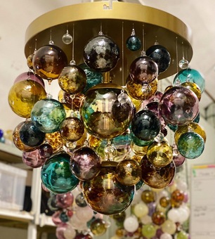 A contemporary chandelier using blown glass spheres in ambers, teals and plums.  This bespoke chandelier features a bronze frame.