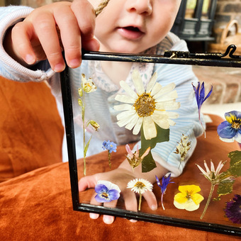 Baby holding a pressed flower frame to the camera