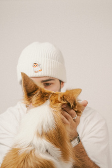 Men in embroidered beanie with cat embroidery petting a dog