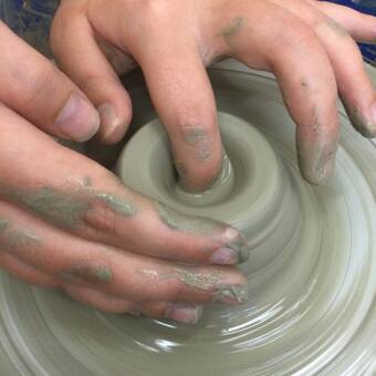 hands forming the clay on a potter's wheel on a pottery course