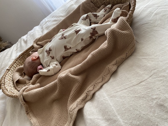 Newborn baby in a changing basket on the bed