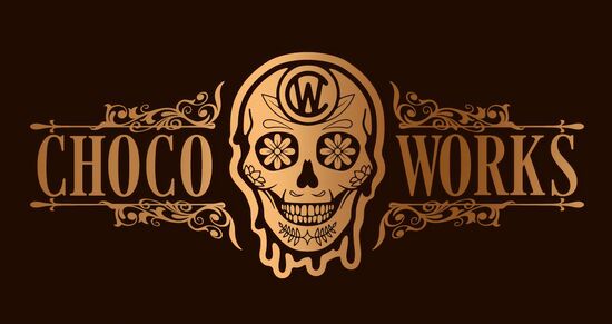 An image of a golden stylised skull with intricate patterns on it and around it. The words "Choco Works" are included side-by-side, which are also in gold.