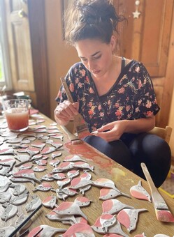 Artist working at table painting ceramic birds 