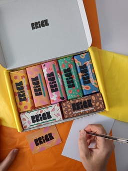 a box of brick chocolate bars with a person writing a gift note from above