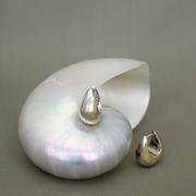 Mixed rhodium & 18 carat gold plated teardrop hoop earrings displayed on a shell