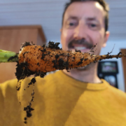 Happy man holding home grown carrot