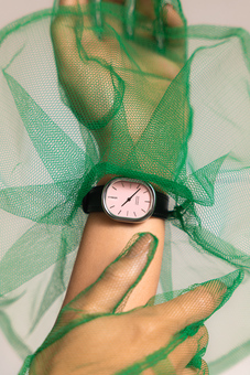 woman wearing a women's watch with a pink dial, silver case and black strap and a pair of green tulle gloves