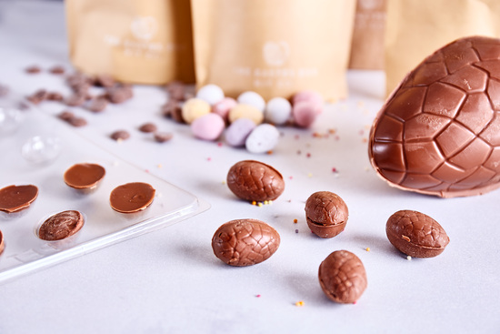 A medium sized chocolate Easter egg spread across the table with mini chocolate eggs and sprinkles